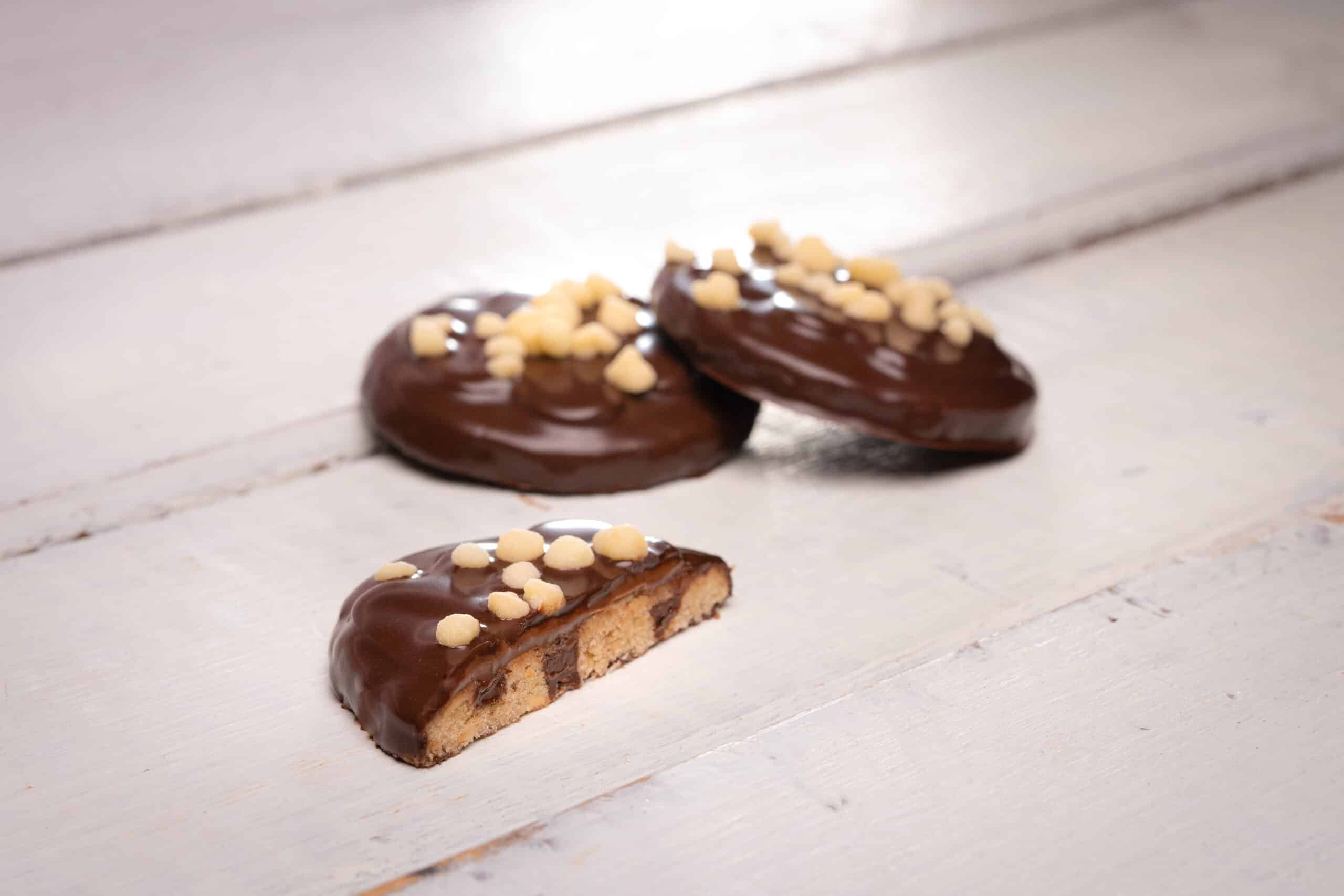 drei Cookies Schokoladenüberzug angebissen weiss Holzbrett neutral hell Produktfotografie Schweiz Zürich BeLighted